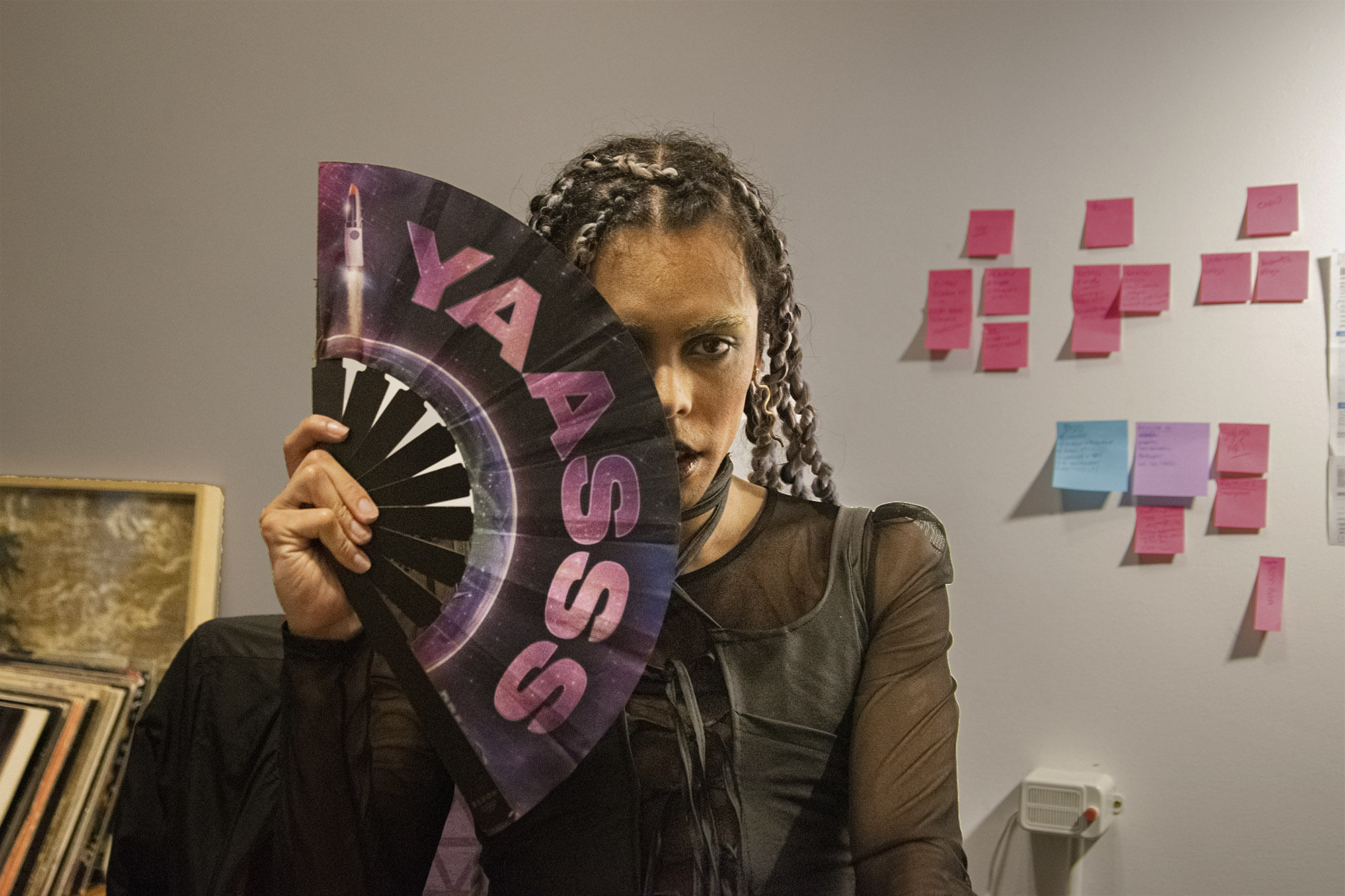 Dragqueen holding a fan saying yaasss covering half his face with it