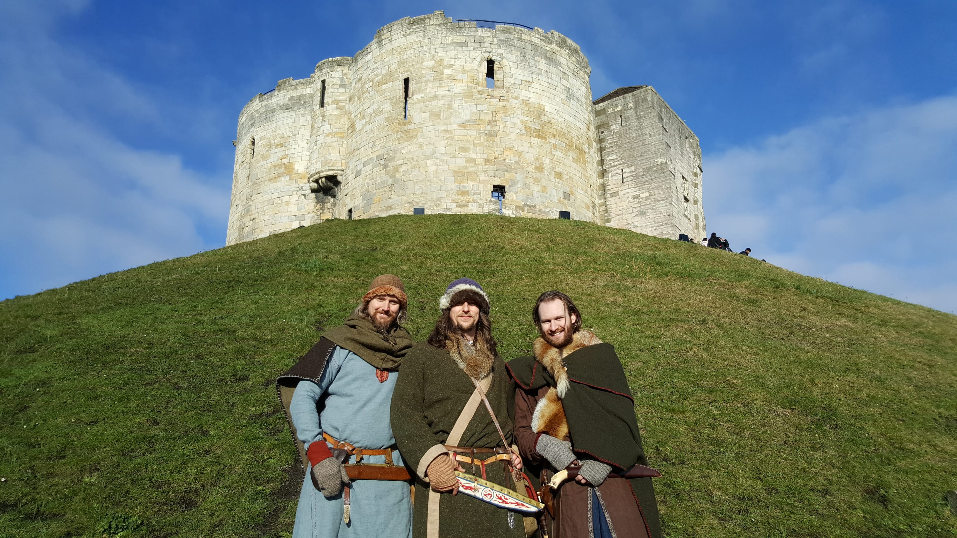 Three viking men stood in front of Clifford's Tower, a Norman Keep, in York.