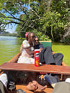 Two happy travelers enjoying a relaxing boat ride on Lake Duluti surrounded by lush green foliage.