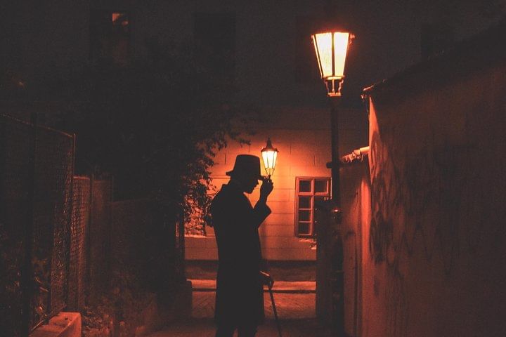 Old lantern lighting narrow Prague street during ghost tour