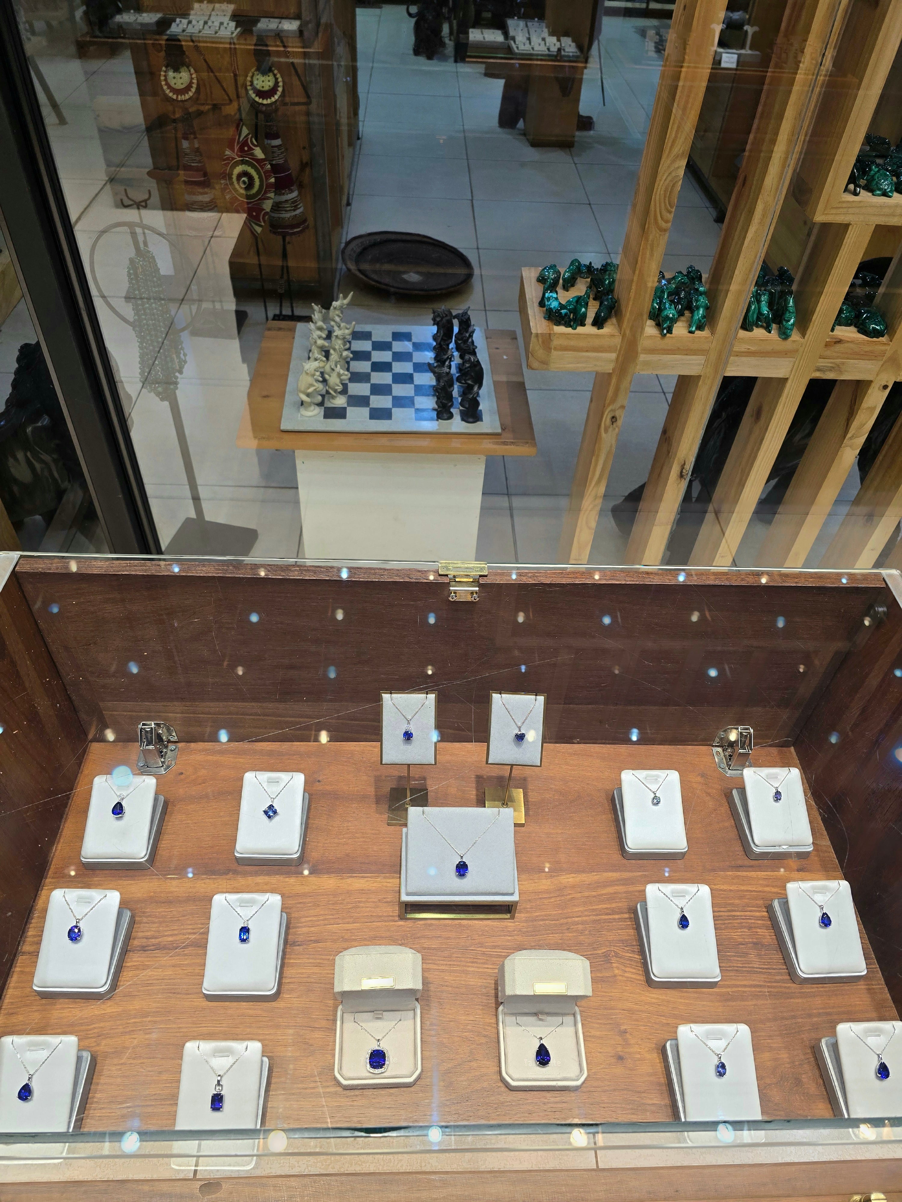A glass display counter containing handcrafted Tanzanian jewelry, rings, and souvenirs set on individual white stands.