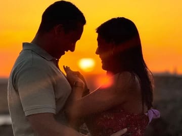 A newly engaged couple sharing a tender moment on a private boat in Malta, as she admires her ring while being lovingly embraced during a romantic sunset.
