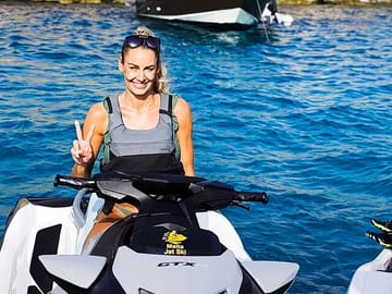 A lady flashing a peace sign while riding her jet ski at Blue Lagoon Malta, enjoying the fun and freedom of the Jet Ski Safari.