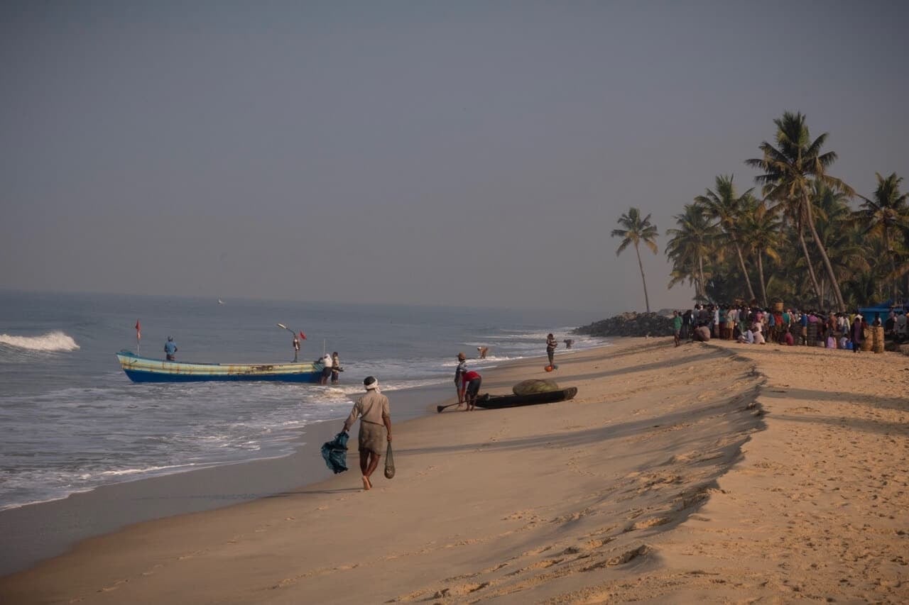 Fishing boats and local activity along a palm-lined Kerala beach