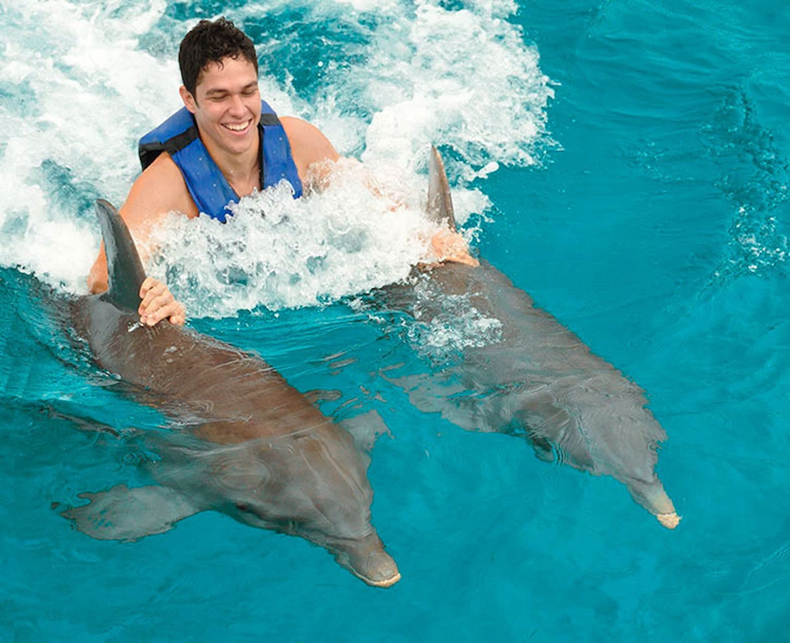 Tourist enjoying a ride with two dolphins in Punta Cana, Bávaro