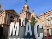Standing in from of a palace like building with a big sign explaining that it is the national art museum of Barcelona.