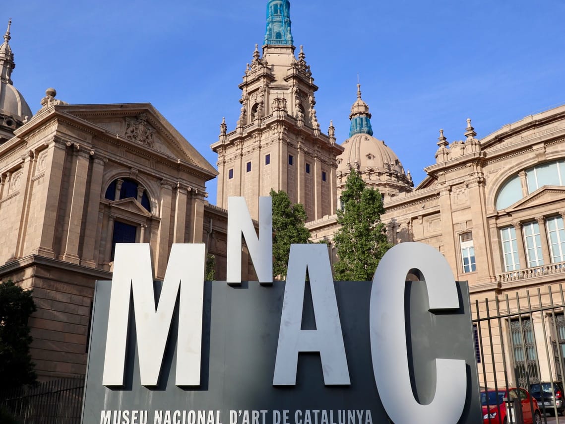 Standing in from of a palace like building with a big sign explaining that it is the national art museum of Barcelona.