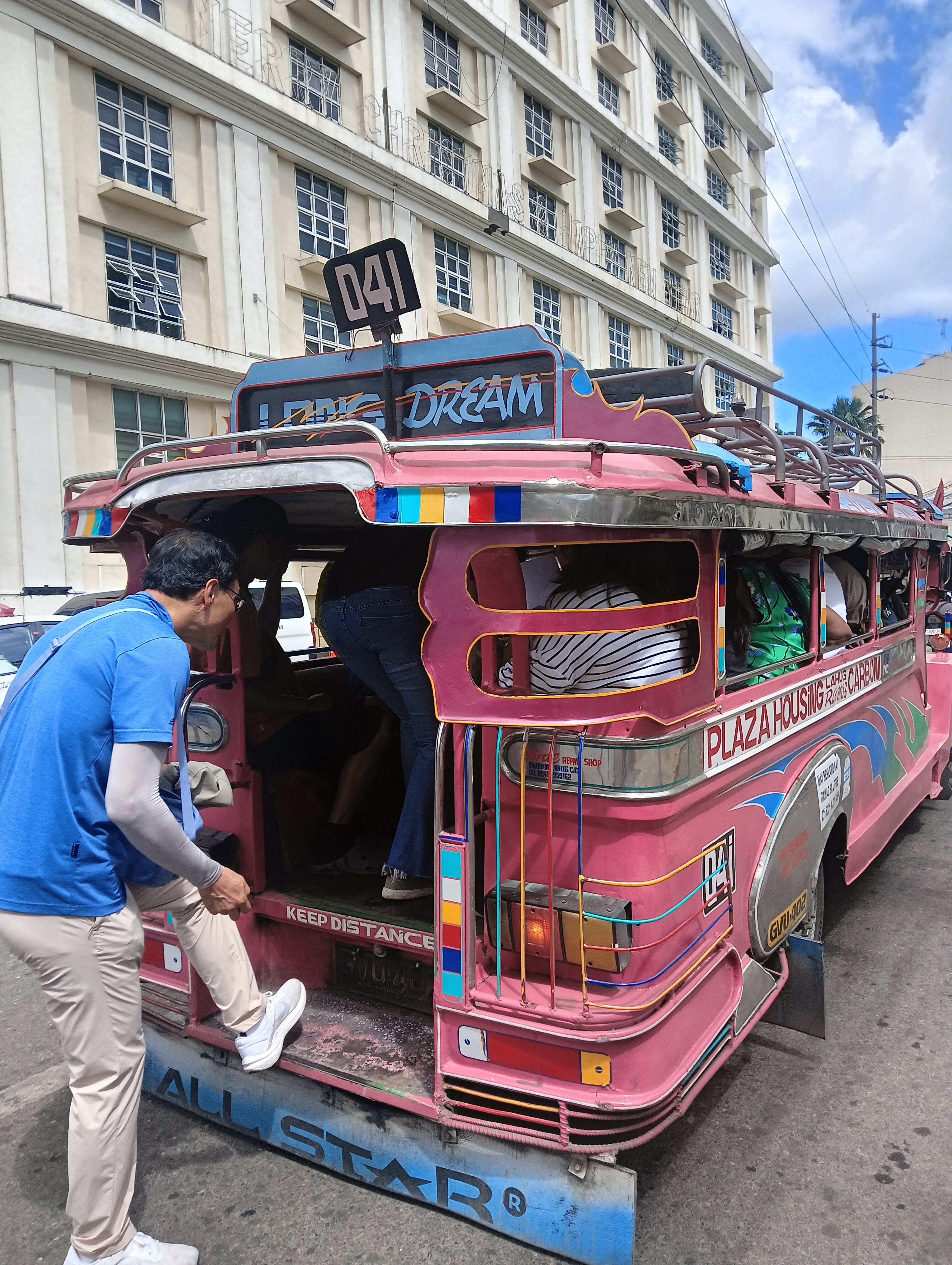 A traveller boards a colorful traditional jeepney with passengers in Cebu City.
