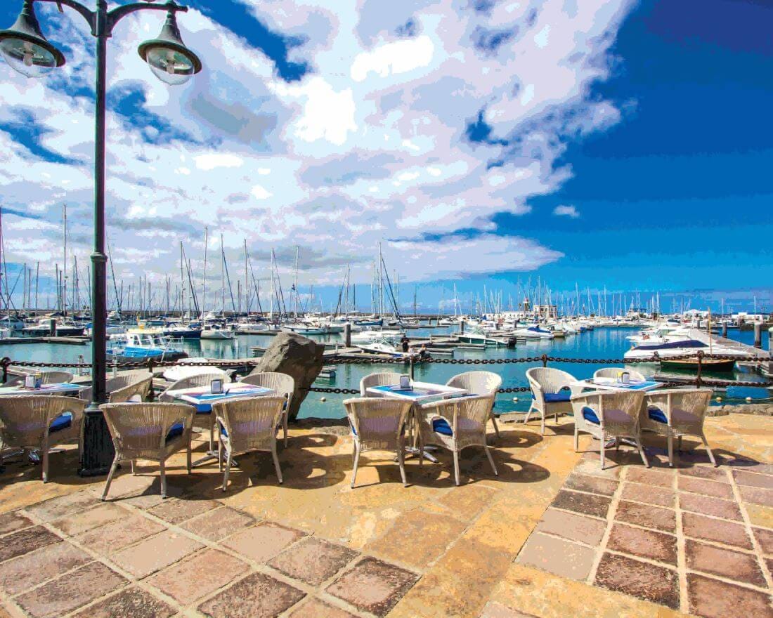 Outdoor café tables and chairs at a waterfront terrace in Lanzarote