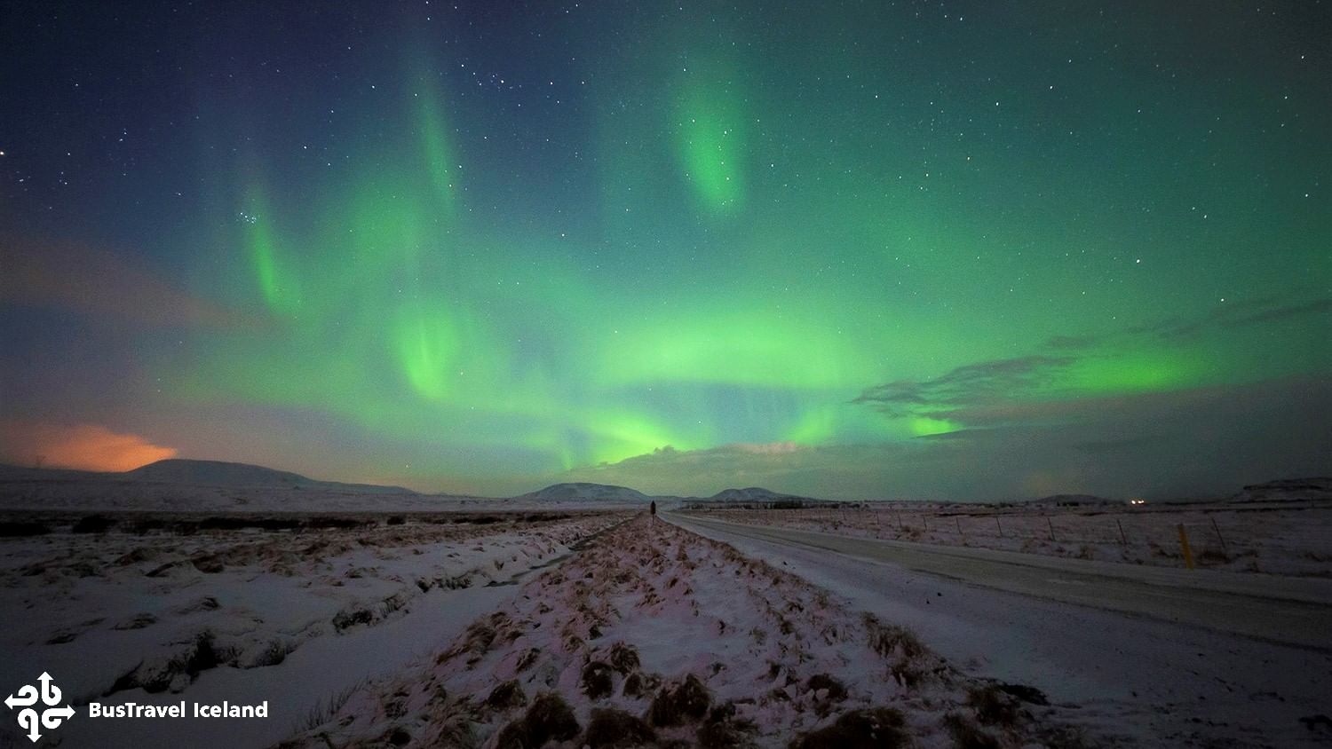 Green aurora borealis over a snowy road in Iceland