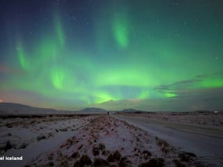Green aurora borealis over a snowy road in Iceland