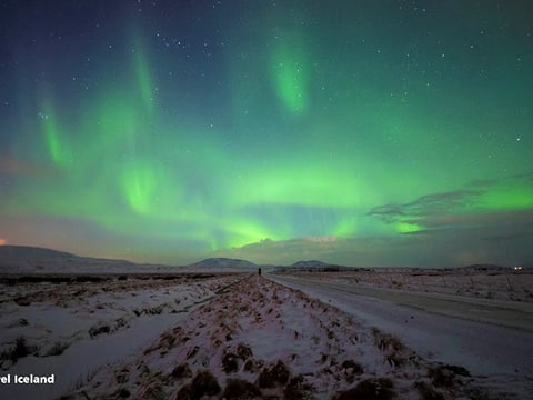 Green aurora borealis over a snowy road in Iceland