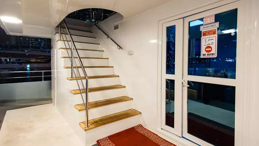White stairs with wooden steps and a metal handrail lead upward beside a closed glass door at Alexandra Sea Lounge.